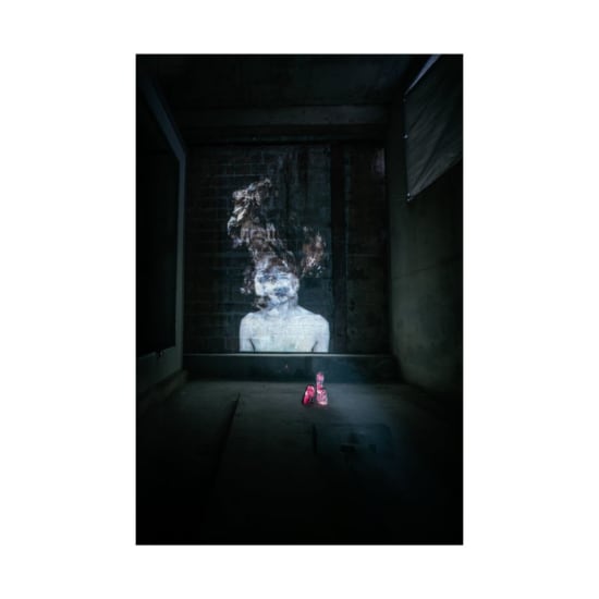 A surreal projection of a ghostly figure illuminating a dimly lit, industrial room.