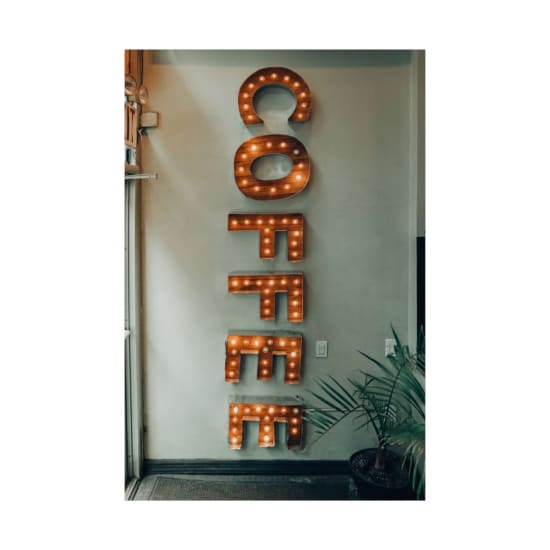 Warm, vintage-style illuminated coffee sign in a New York coffee shop interior.