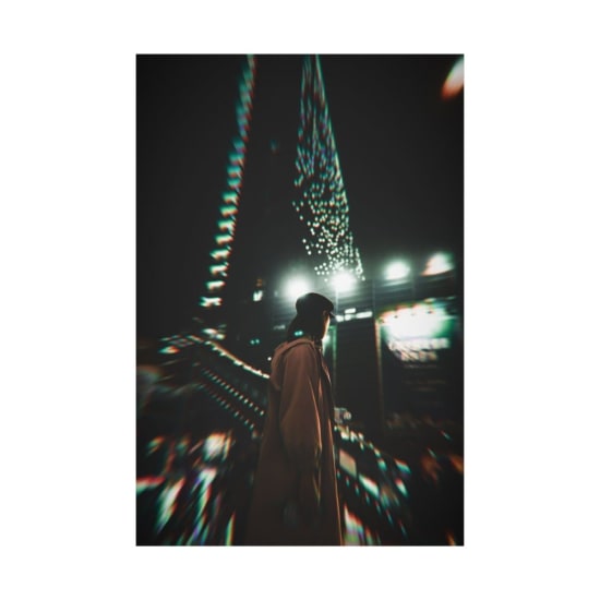 Blurry cityscape at night with light trails and a lone figure adding mystery and intrigue.