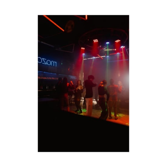 Diverse group enjoying a lively night out at a trendy nightclub with colorful lighting.