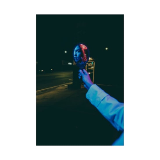 Creative photo of a woman's reflection in a handheld mirror at night, illuminated by streetlights.