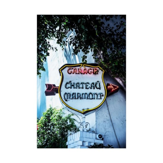 Vibrant neon sign of Chateau Marmont in LA surrounded by greenery.