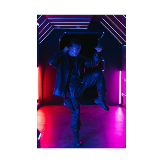 A person striking a bold pose in a neon-lit corridor, showcasing futuristic cyberpunk fashion style.