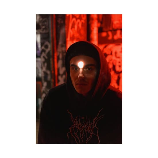A dramatic portrait of an adult wearing a hoodie, surrounded by neon red graffiti, creating a mysterious atmosphere.
