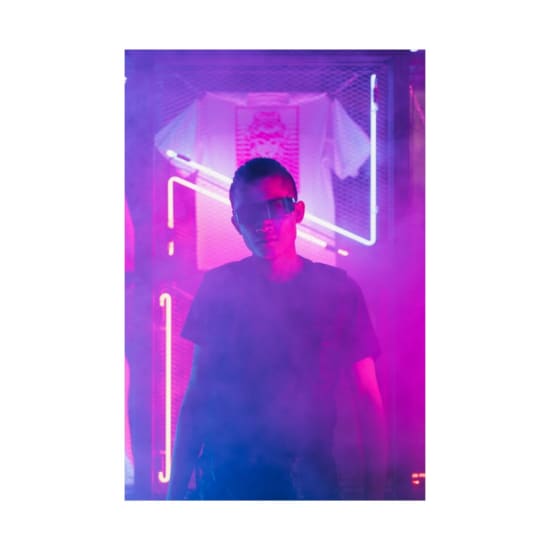 Futuristic portrait of a man wearing sunglasses in a neon-lit environment.