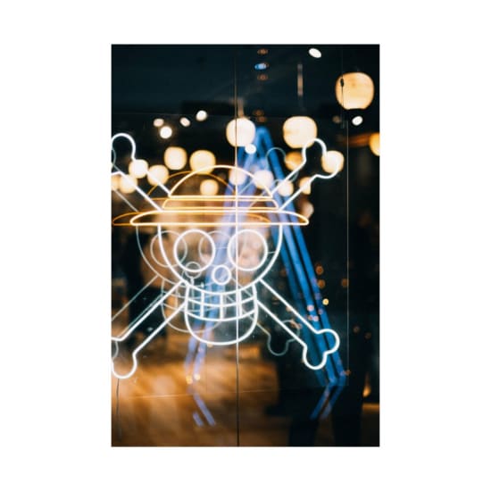 Vibrant neon skull and crossbones sign illuminated at night in an urban setting.