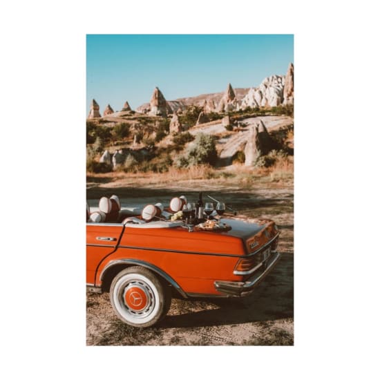 A vintage convertible parked near Cappadocia's rock formations, featuring a picnic setup with wine.