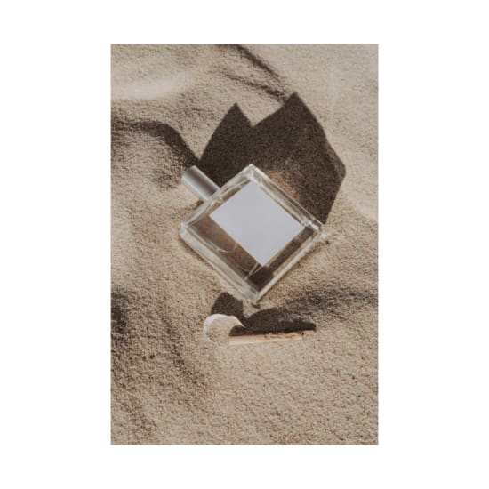 Minimalist perfume bottle on sand captures elegance and luxury.