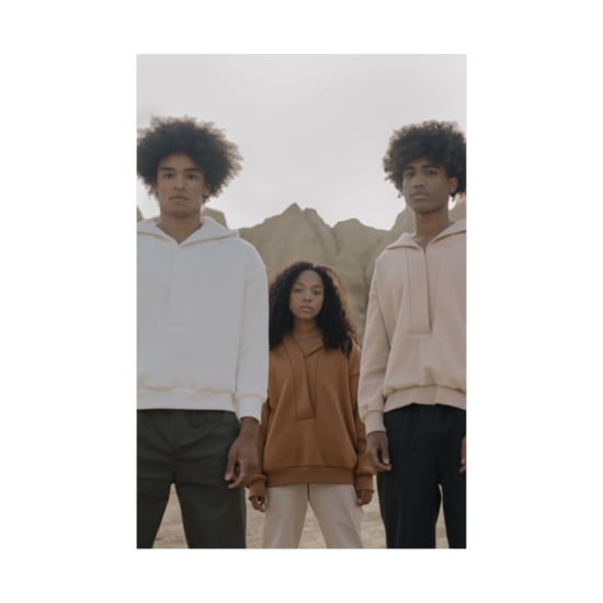 Three teenagers with afro hair posing in stylish apparel against desert rock formations.