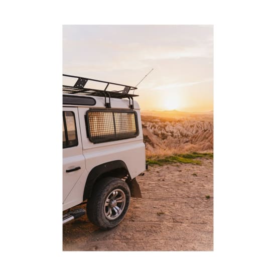 White SUV parked with a breathtaking view of Cappadocia during sunset, perfect for adventure enthusiasts.