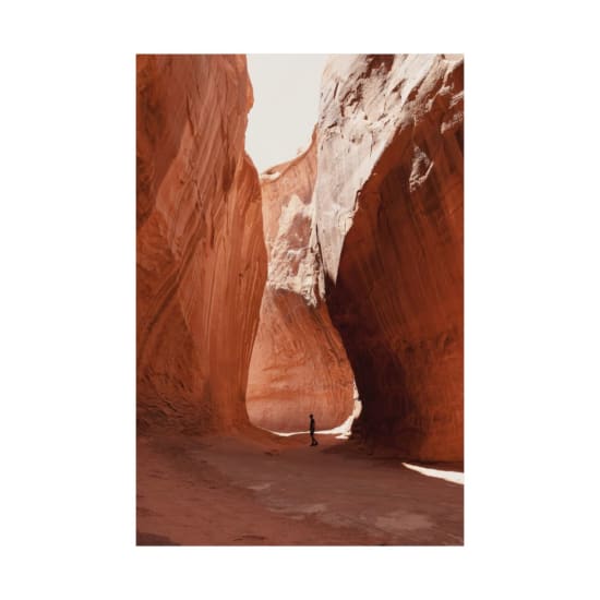 A solitary hiker walks through the stunning rock formations of a canyon near Lake Powell, Utah.