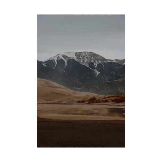 Scenic view of sand dunes with snowy mountains in the background, perfect for travel and nature themes.