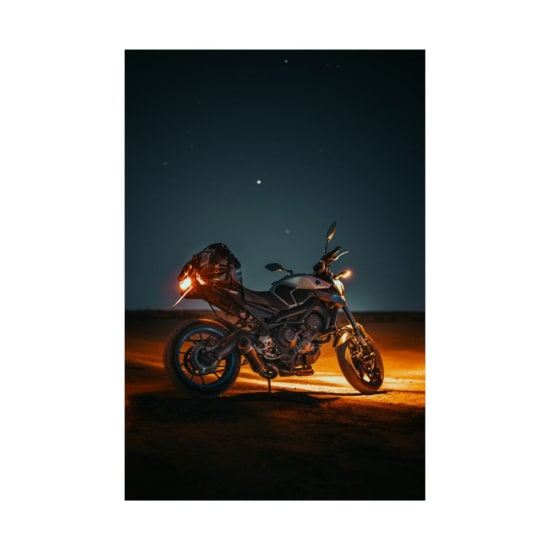 Stunning nighttime shot of a motorbike highlighted under the stars in a desert landscape.