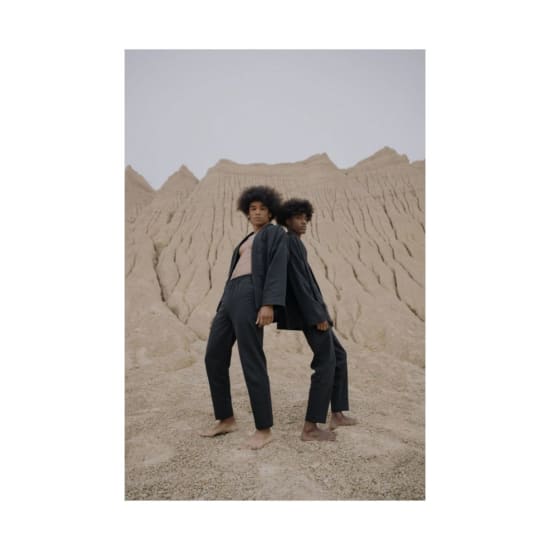 Two models posing in stylish outfits against a striking desert backdrop.