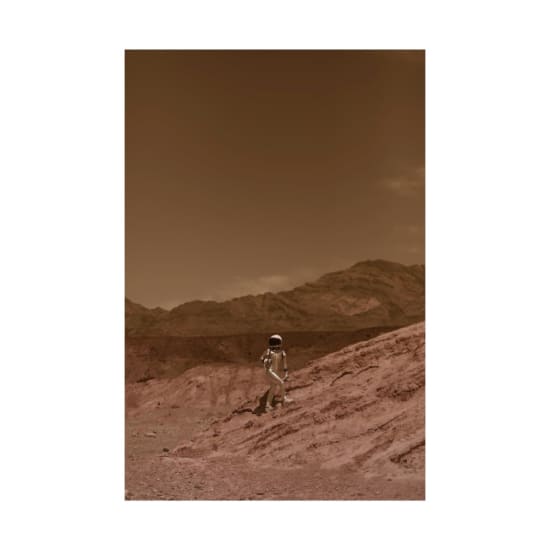 An astronaut stands on a barren, Mars-like terrain with hills in the background, evoking a sense of interplanetary exploration.
