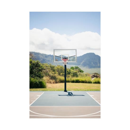 Outdoor basketball court with stunning mountain backdrop on a sunny day.