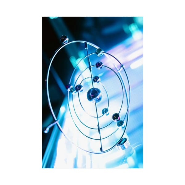 A futuristic metal orbital sculpture illuminated by neon lights creating a vibrant visual effect.