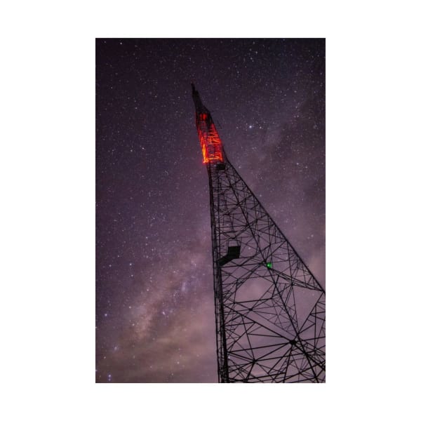 A communication tower illuminated against a starry night sky.