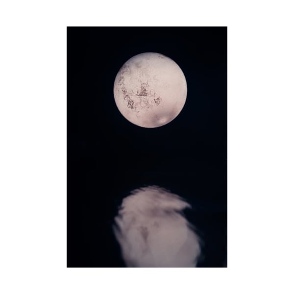 A stunning view of the full moon reflecting on calm water at night.