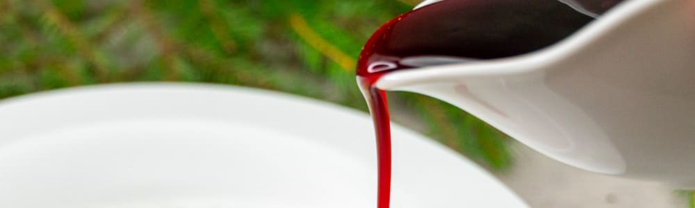 Bilde av noen som heller rød saus over en riskrem.