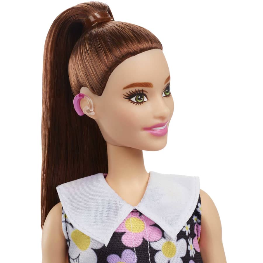 A Barbie doll stands with a visible hearing aid, from the Mattel store website