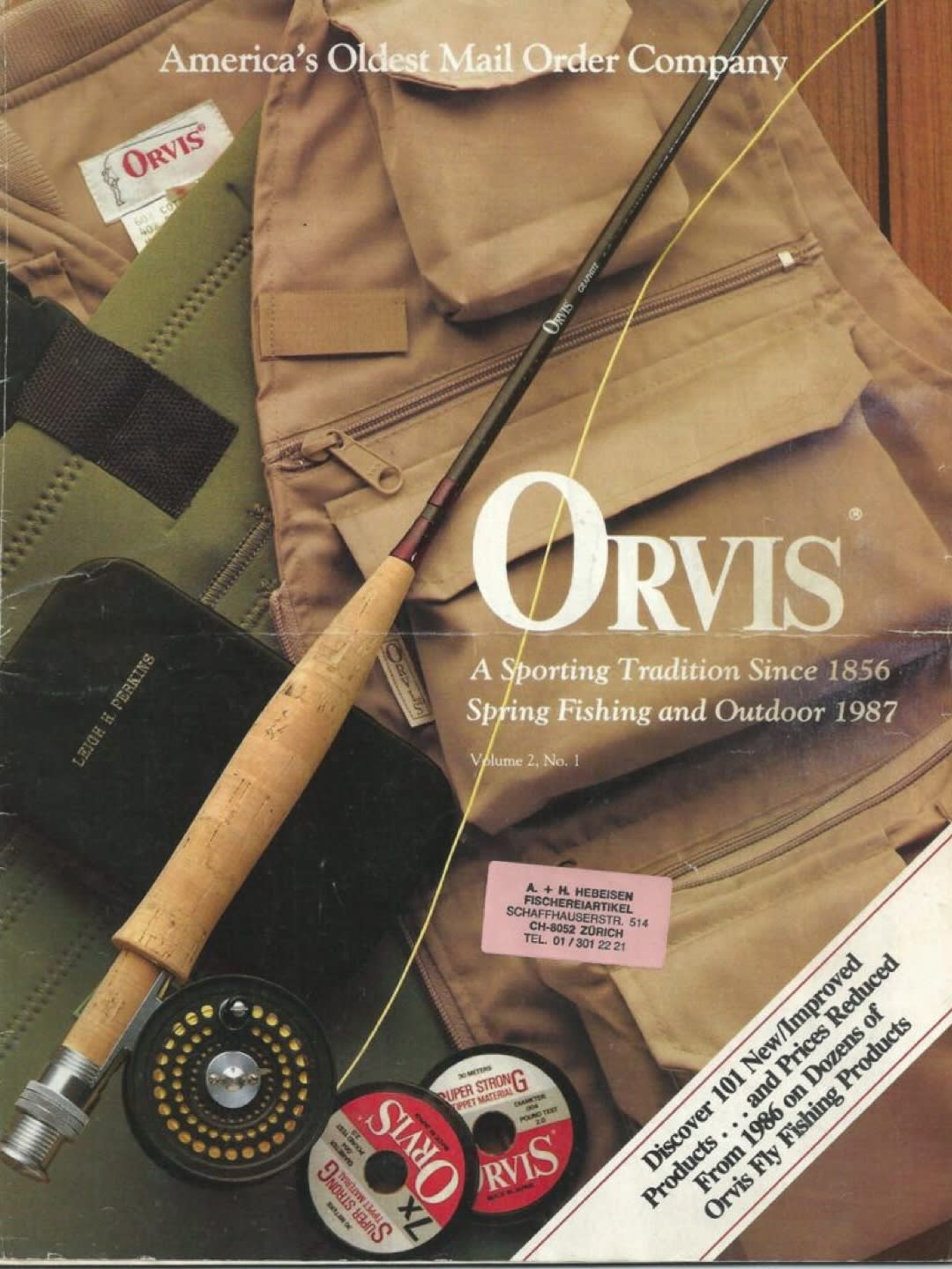 A fly fishing rod and reel rest on a fishing vest, with the Orvis logo and catalog information visible in the background.