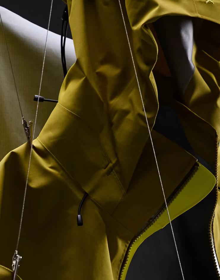 Close-up of an olive green jacket with a partially unzipped bright yellow-green front zipper.