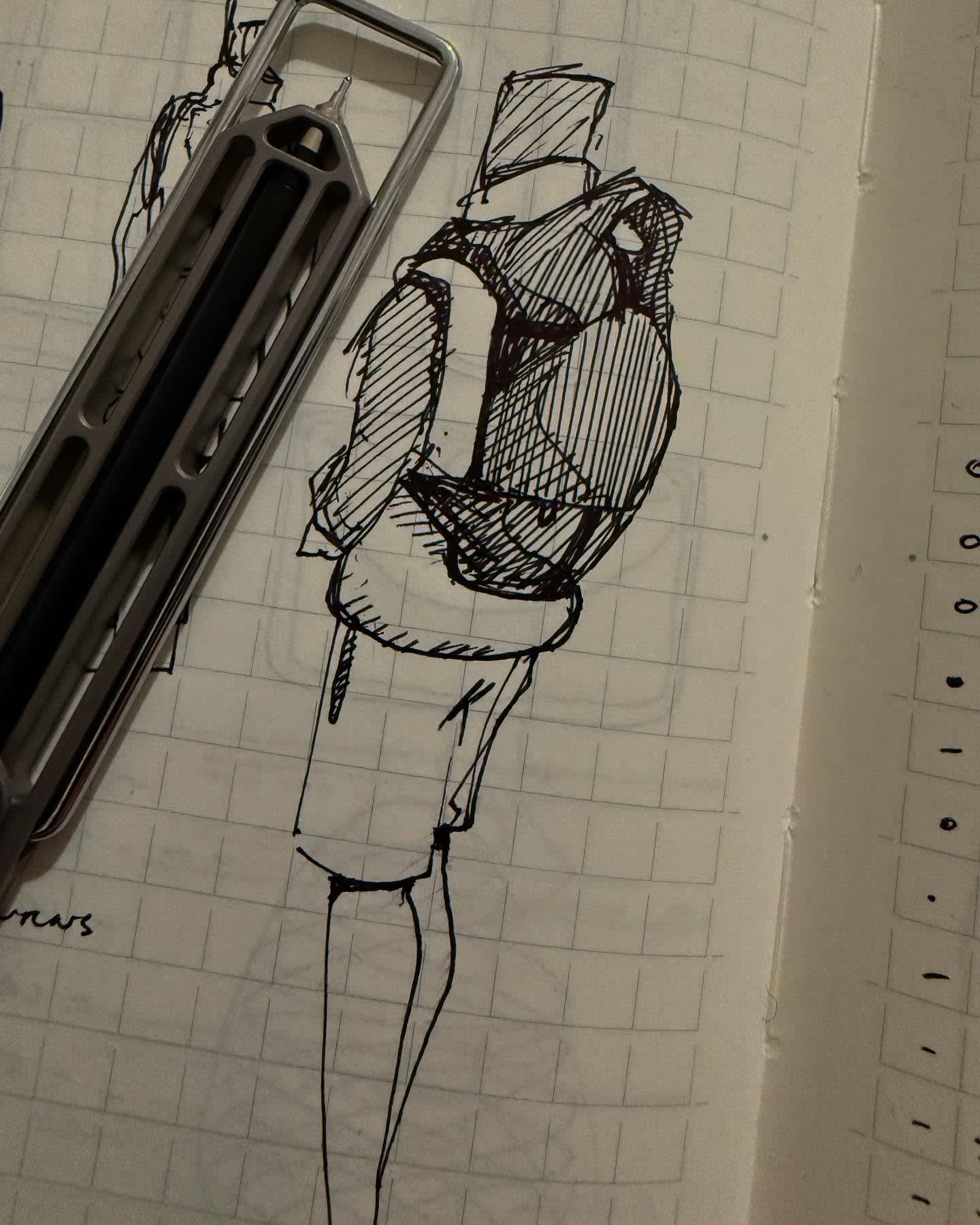 A silver mechanical pencil rests beside a black ink sketch of a figure on a piece of grid paper.