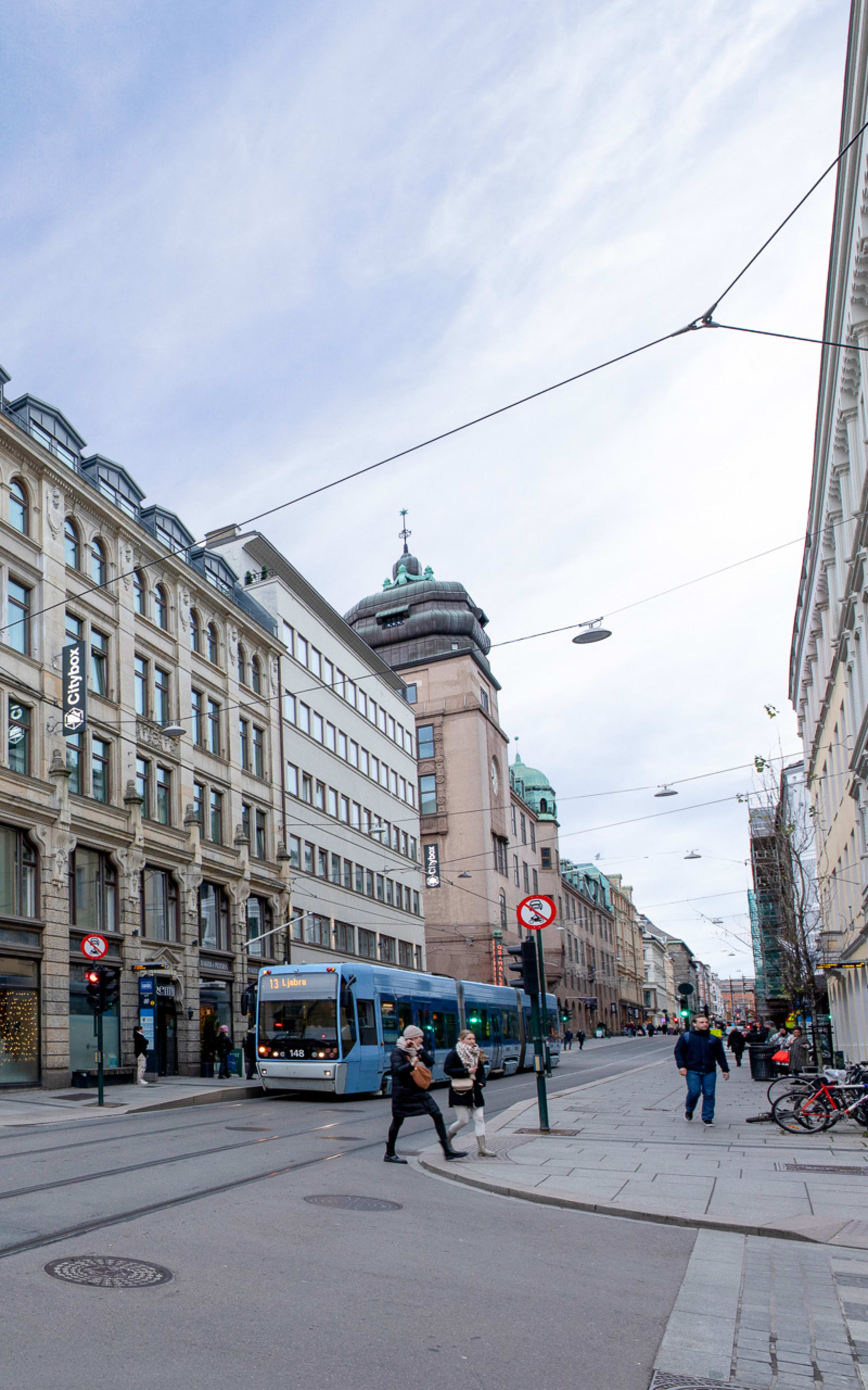 Fasade Citybox hotell sett fra Dronningens gate med trikk og lyskryss utenfor