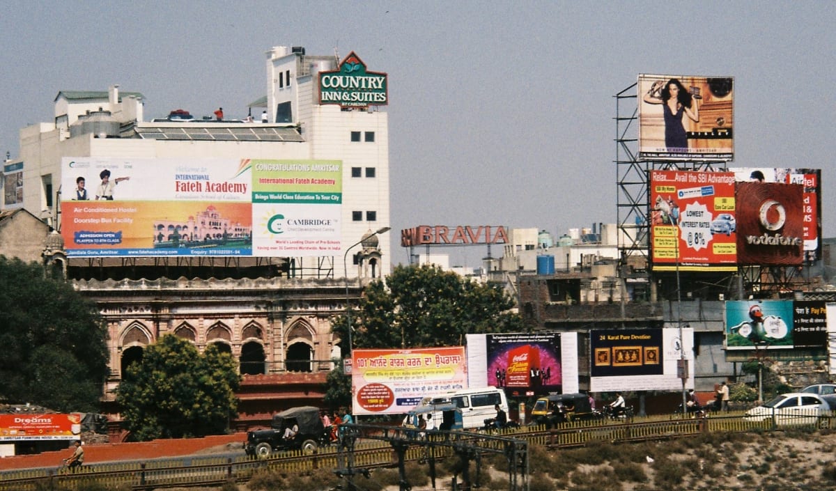 Advertising hoardings for schools, banks and phone brands above a busy road in Amritsar, Punjab