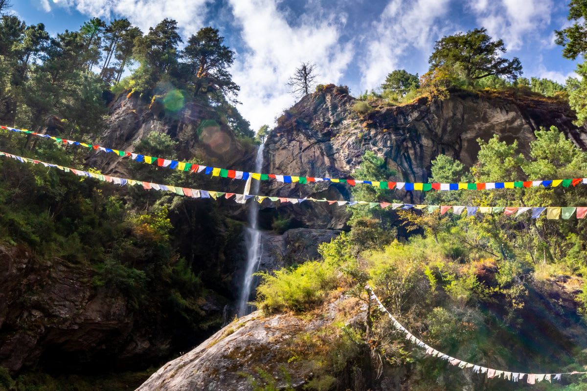 Wasserfall und Gebetsfahnen im Tal des Dudh Koshi