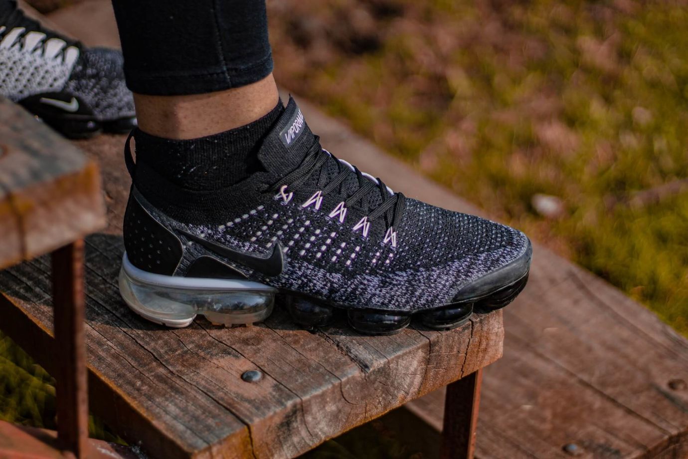 Fuß in dunklen Nike Sneakern auf Holzstufen