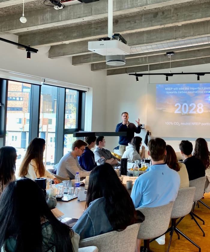 Picture of UVA McIntire M.S. in Commerce students sitting around a long table and listening to executives at the NERP offices in Copenhagen, Denmark.