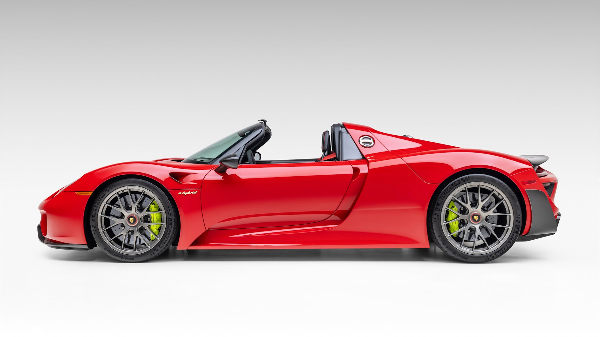 Side profile of the Guards Red 2015 Porsche 918 Spyder Weissach for sale on Mecum
