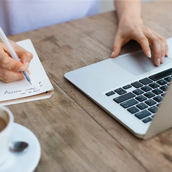 A woman using a computer and taking notes