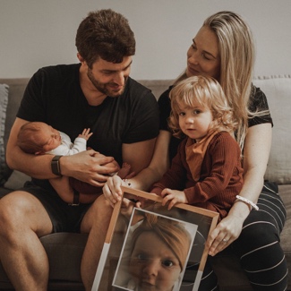 A person and person holding a baby and a picture of a childDescription automatically generated