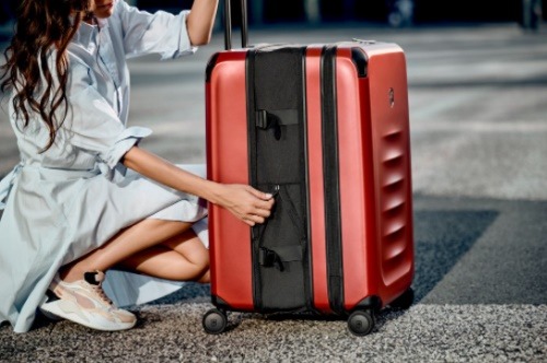 A person kneeling next to a suitcaseDescription automatically generated