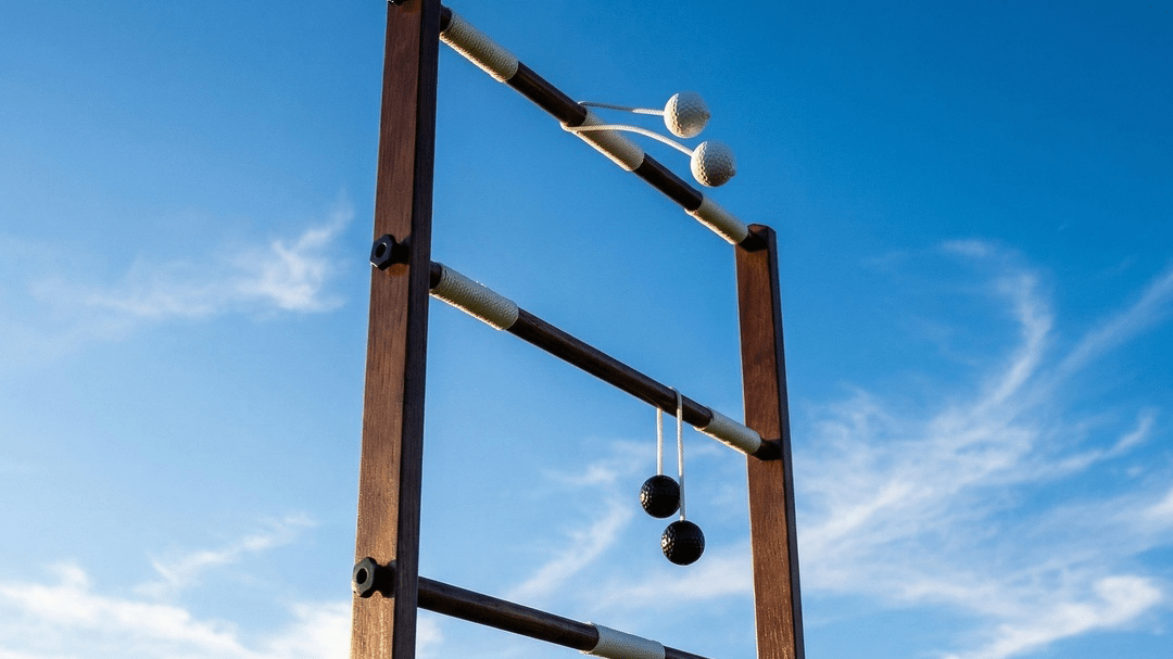 A white bola on the top rung of a wooden ladder toss goal, and a black bola on the middle rung