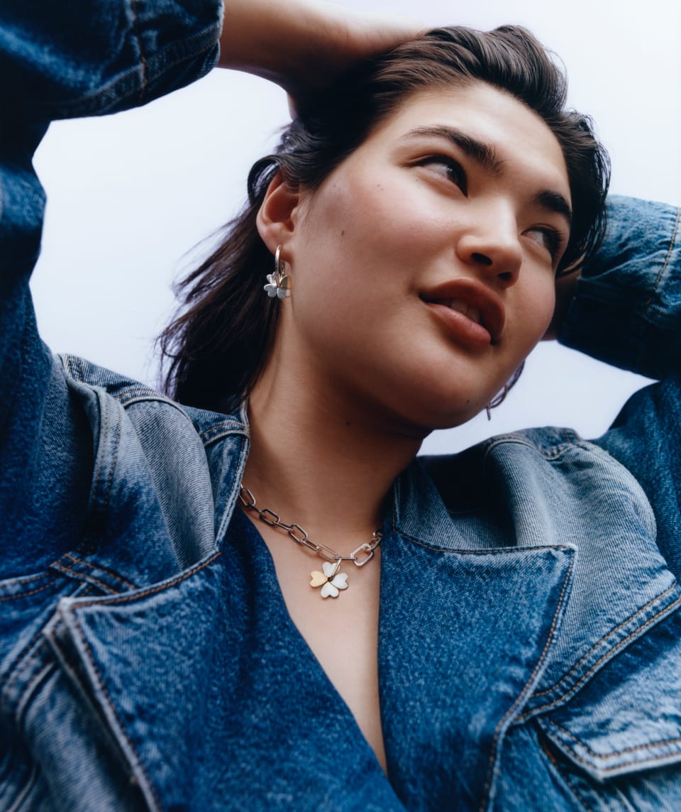 Model is wearing a denim jacket and Mejuri X Ganni Hoops.