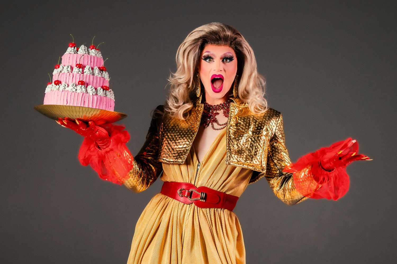 Drag queen Valerie Hex holding a cake.