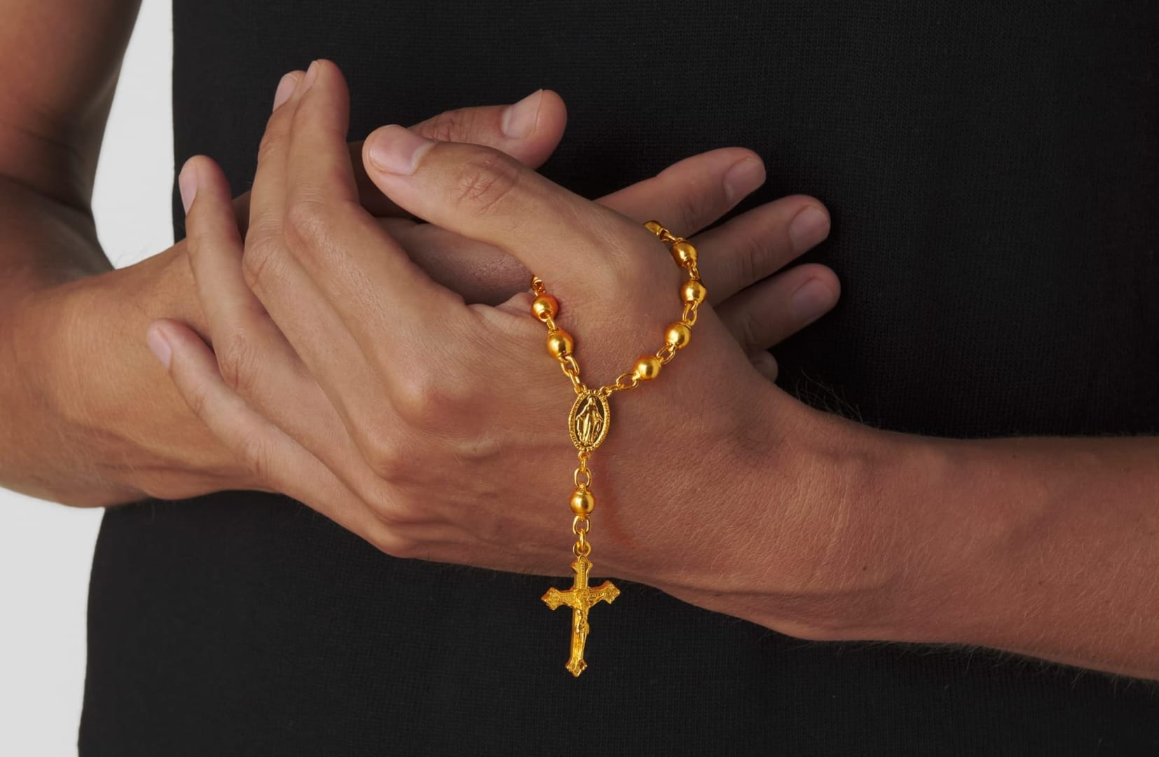 Menē Saints Collection 24k gold Palm Rosary held in hand.