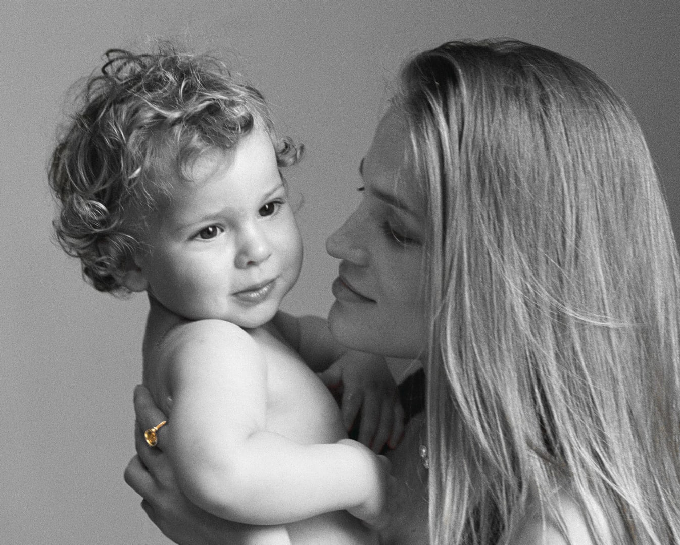 Mother holding child in Menē 24k gold jewelry from the 2026 Mother’s Day Collection.