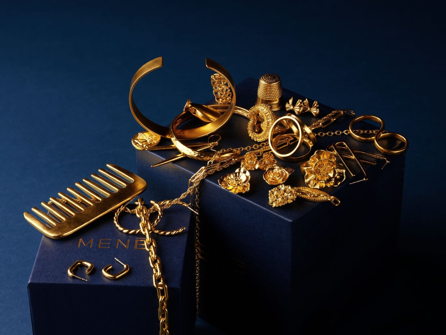  selection of Menē 24k gold jewelry, including rings, chains, and bracelets shaped to be worn, kept, and passed across generations.