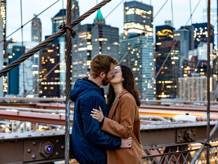 couple kissing on the Brooklyn Bridge at night