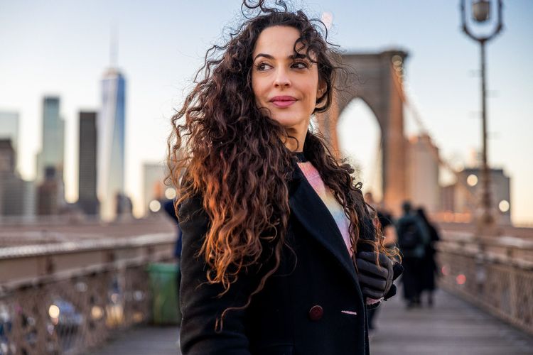 women standing on Brooklyn Bridge with big curly hair 