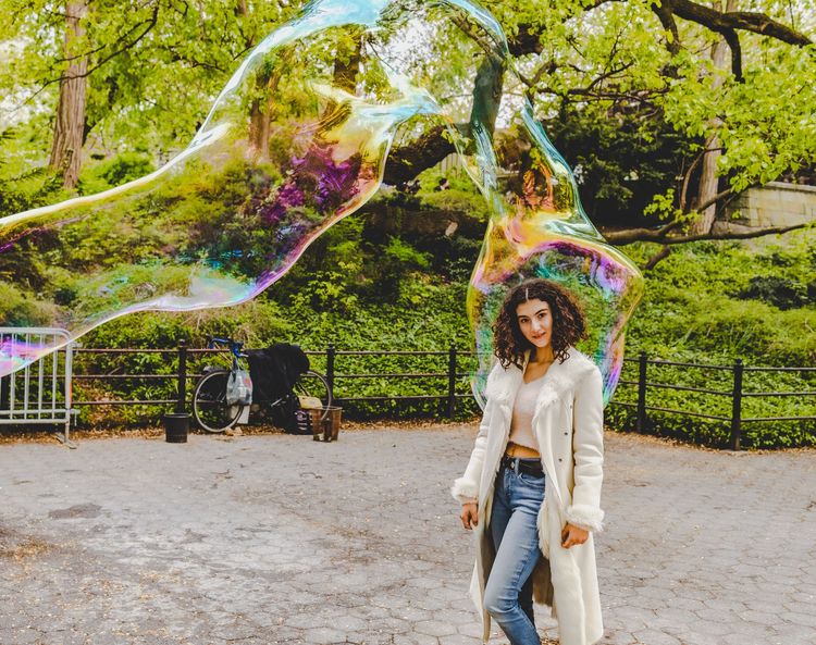 girl in soap bubbles in Central Park by bow bridge 