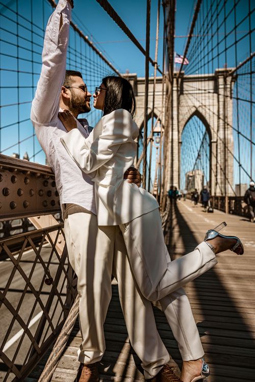 couple wearing white on the Brooklyn Bridge guy  holding the rope 