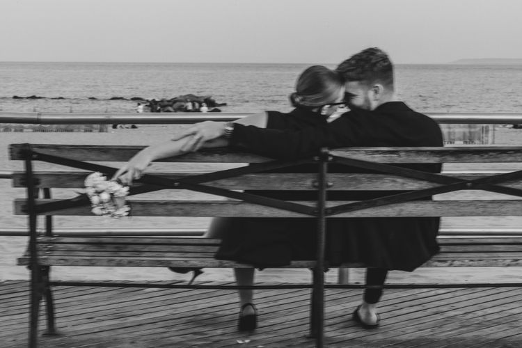 girl holding flowers in Coney Island sitting on a bench 