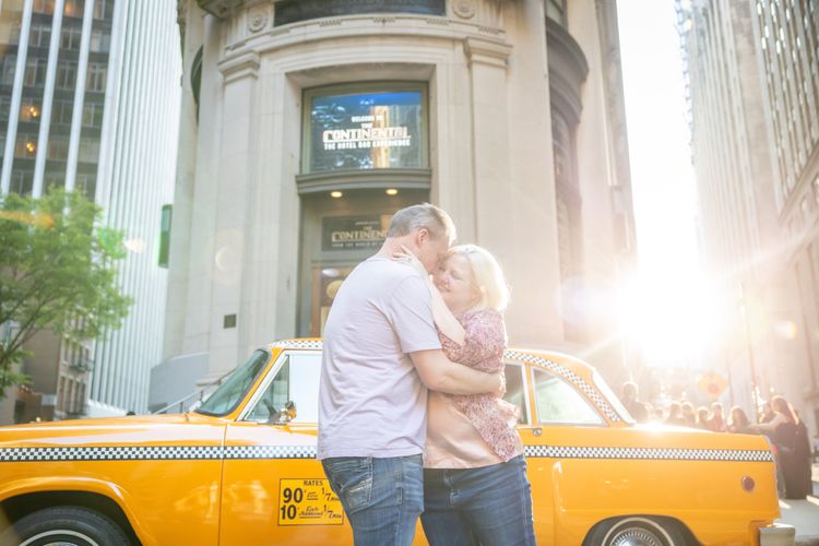 couple posing by old, vintage, yellow,  New York City cab in Wall Street 