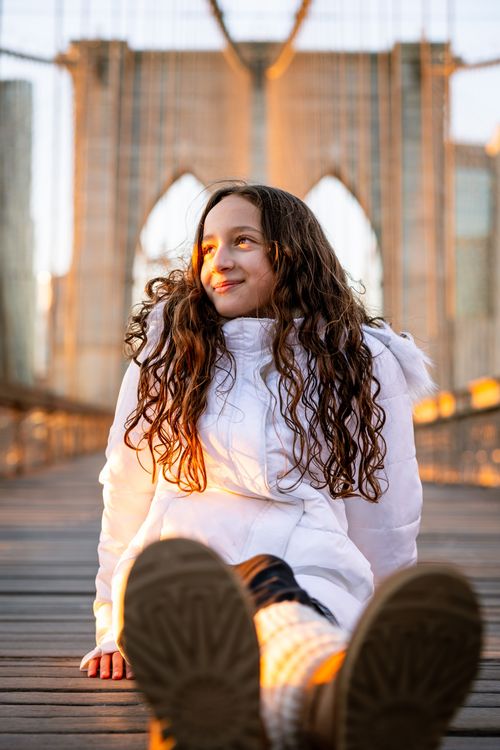 girl taking a picture on the Brooklyn Bridge during golden hour in New York City 